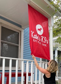 a woman hangs a red flag on the porch of a house